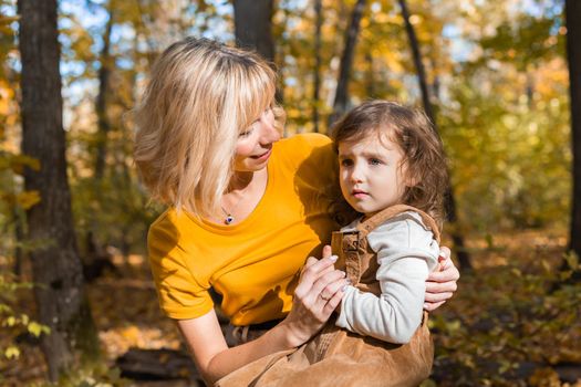 Beautiful lifestyle autumn photo mother and child walks evening in the park, warm sunlight