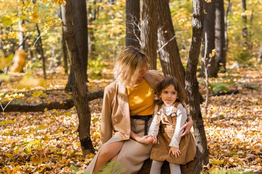 Beautiful lifestyle autumn photo mother and child walks evening in the park, warm sunlight