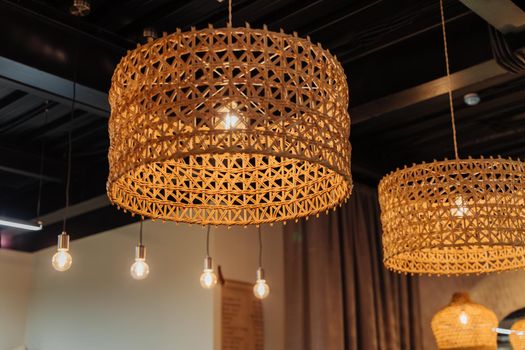 Beautiful interior of the confectionery studio. Cozy lamps in a coffee shop. Wicker lampshades on lamps in a cafe. Family bakery.