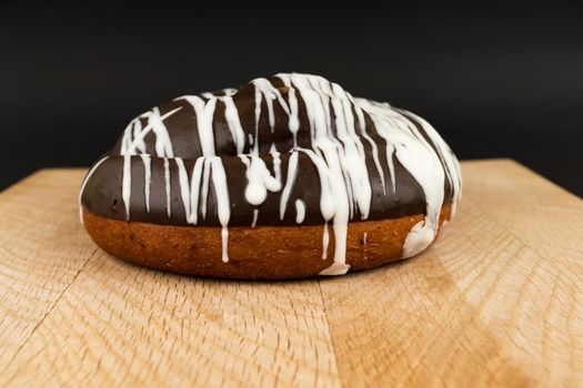 bun covered with chocolate on a wooden board