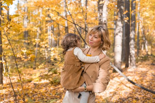 Beautiful lifestyle autumn photo mother and child walks evening in the park, warm sunlight