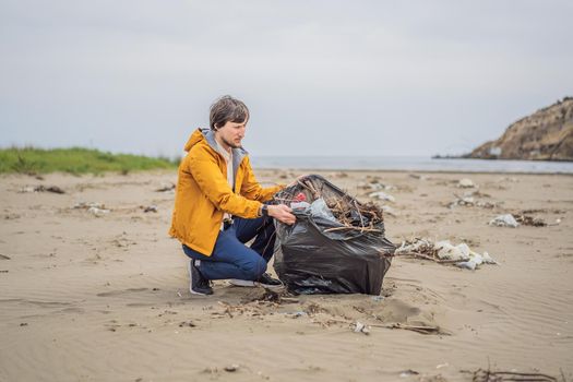 Plastic garbage. Sea and ocean pollution. Beach clean up. Young man picking used plastic bottles on sand shore. Environmental activist collecting rubbish. Save our Earth. Nature protection.