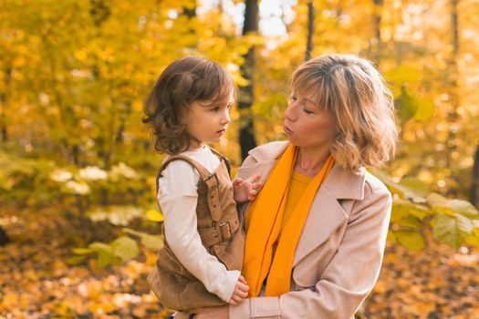 Mother with child in her arms against background of autumn nature. Family and season concept