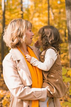 Mother and little daughter enjoying nice autumn day in a park. Season, family and children