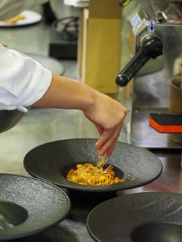 closeup of a chef hand wearing gloves serving and decorating a plate of pasta