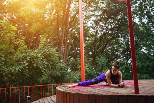 A young woman in doing yoga in the yard on the veranda