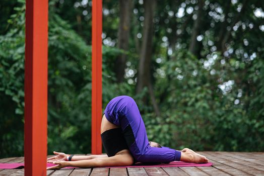 A young woman in doing yoga in the yard on the veranda