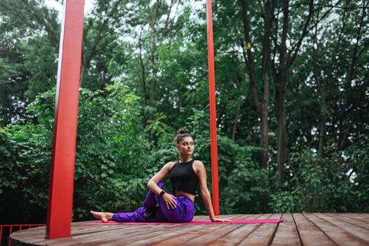 A young woman in doing yoga in the yard on the veranda
