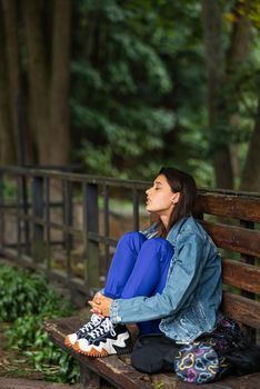 Pensive woman sitting on a bench in a park