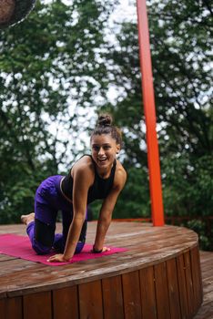 A young woman in doing yoga in the yard on the veranda