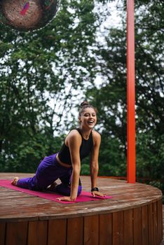 A young woman in doing yoga in the yard on the veranda