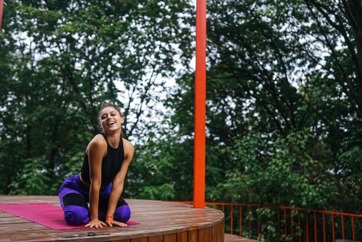 Young woman sitting on the wooden floor on the veranda after training
