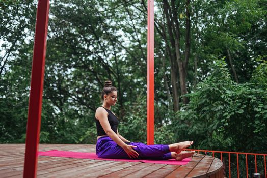 A young woman in doing yoga in the yard on the veranda