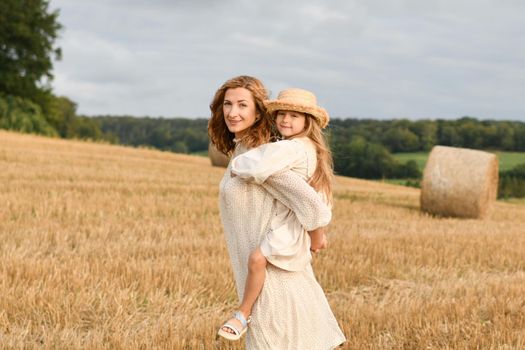 Mother holds daughter in her arms in a field with wheat Mothers day