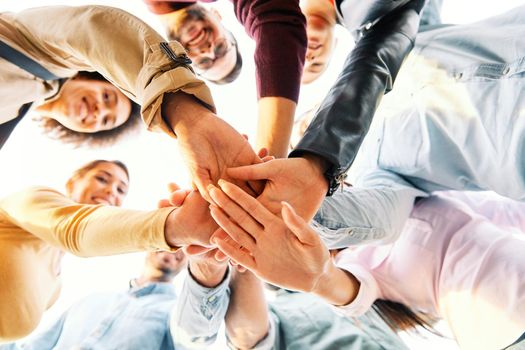 Close up of hands of young people friends holding together, unity teamwork support concept