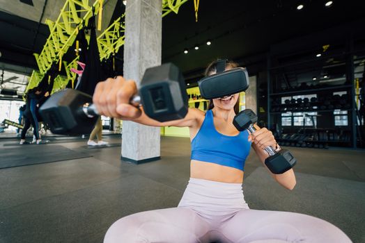 Portrait view of the woman wearing glasses of the virtual reality exercising with dumbbells at gym.
