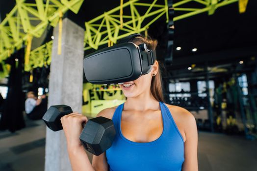 Portrait view of the woman wearing glasses of the virtual reality exercising with dumbbells at gym.