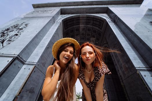 Portrait of two young beautiful smiling hipster female in trendy summer clothes.Sexy carefree women posing on street background.