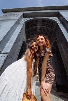 Portrait of two young beautiful smiling hipster female in trendy summer clothes.Sexy carefree women posing on street background.