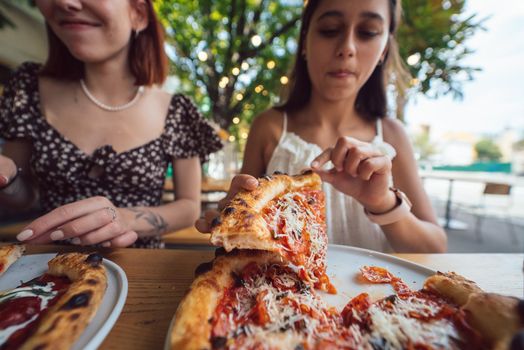 Charming beautiful woman takes a slice of pizza. An attractive girl is hungry and loves the taste.