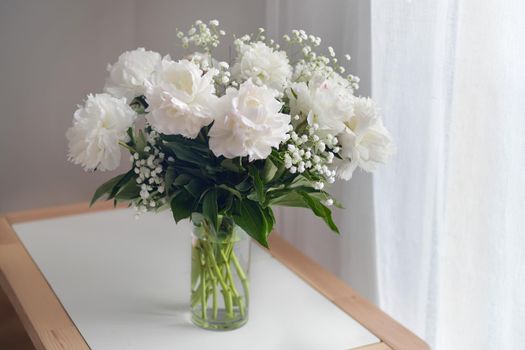 White peonies flowers in a vase on white background