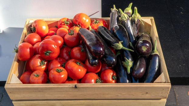 Tomatoes and eggplants, vegetables in a wooden box. High quality photo