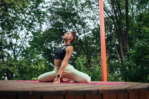 A young woman in doing yoga in the yard on the veranda