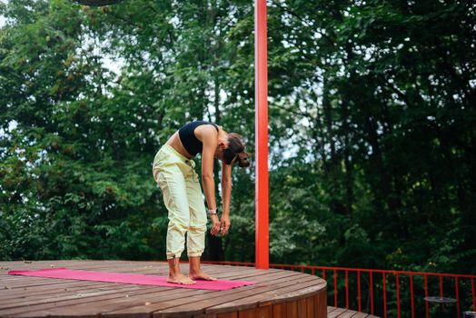 A young woman in doing yoga in the yard on the veranda