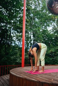 A young woman in doing yoga in the yard on the veranda