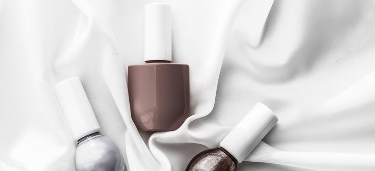 Cosmetic branding, salon and glamour concept - Nail polish bottles on silk background, french manicure products and nailpolish make-up cosmetics for luxury beauty brand and holiday flatlay art design