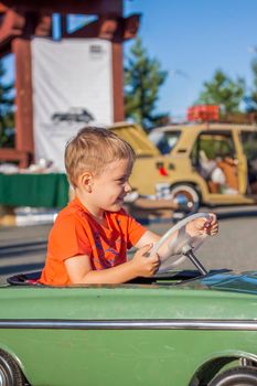 A boy driving a children's car. Joyful emotions. Children, portrait