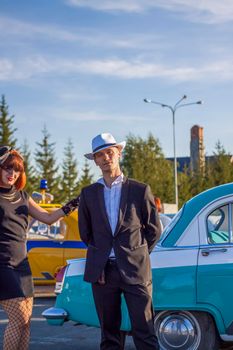 2022-08-12 Tatarstan, Verkhneuslonsky district, Savino village. Resort town "Sviyazhsky hills". Kazan Festival of Historical Cars. A man and a woman in retro clothes pose near cars