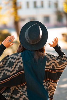 Stylish woman in poncho and hat enjoys autumn nature. People, freedom, lifestyle, travel and vacations concept.