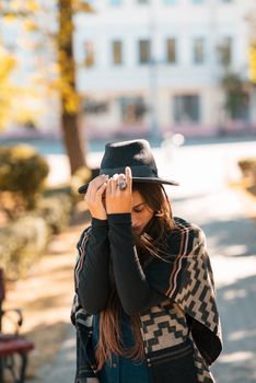 Stylish woman in poncho and hat enjoys autumn nature. People, freedom, lifestyle, travel and vacations concept.