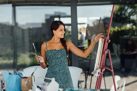 Young female artist with tools posing for camera
