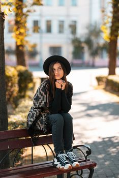 Young woman on a bench in the autumn park. People, freedom, lifestyle, travel and vacations concept.