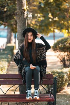 Young woman on a bench in the autumn park. People, freedom, lifestyle, travel and vacations concept.