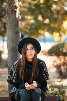 Young woman on a bench in the autumn park. People, freedom, lifestyle, travel and vacations concept.
