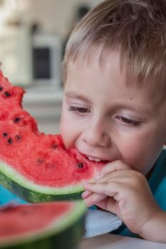 Cute boy eating watermelon at home. Real emotions without posing. children