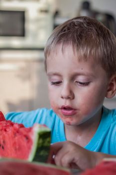 Cute boy eating watermelon at home. Real emotions without posing. children