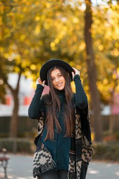 Stylish woman in poncho and hat enjoys autumn nature. People, freedom, lifestyle, travel and vacations concept.