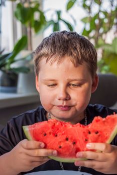 Cute boy eating watermelon at home. Real emotions without posing. children