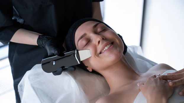 Woman on ultrasonic cleaning procedure. Hardware cosmetology