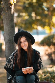 Young woman on a bench in the autumn park. People, freedom, lifestyle, travel and vacations concept.