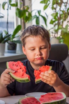 Cute boy eating watermelon at home. Real emotions without posing. children