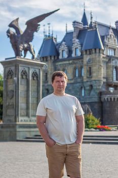 A man on the background of a Gothic-style castle. The territory of the tourist complex.