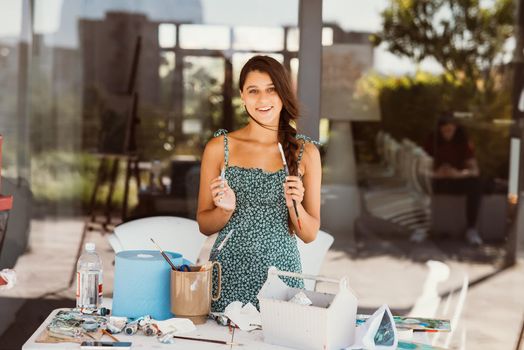 Young female artist with tools posing for camera