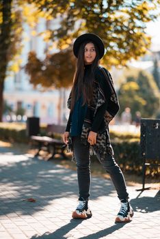 Stylish woman in poncho and hat enjoys autumn nature. People, freedom, lifestyle, travel and vacations concept.