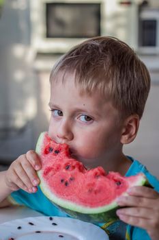 Cute boy eating watermelon at home. Real emotions without posing. children