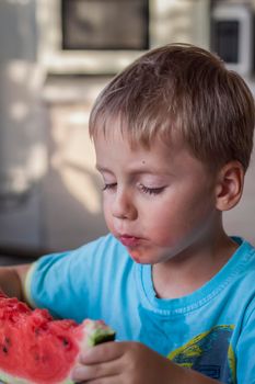 Cute boy eating watermelon at home. Real emotions without posing. children